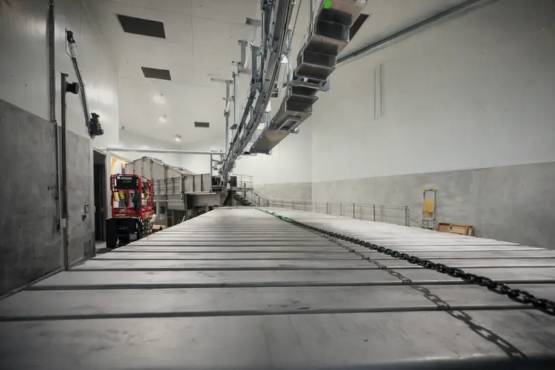 Stainless slat conveyor and overhead line inside a processing facility